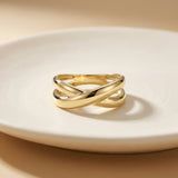 Anillo cruzado en oro amarillo de 14 quilates sobre un plato blanco