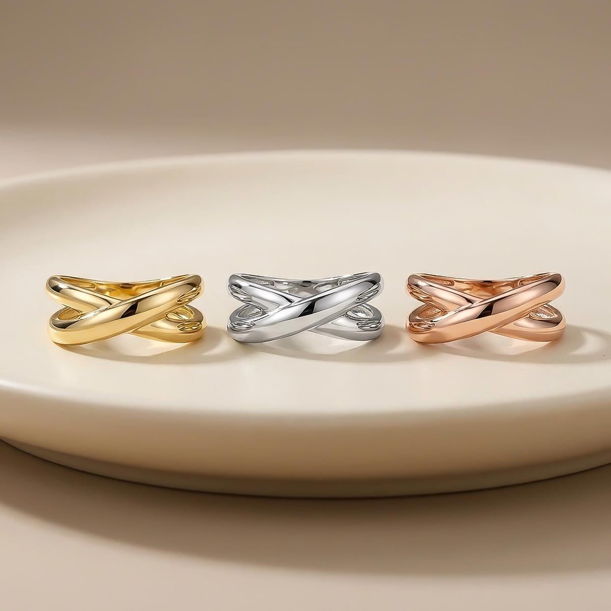 Anillos cruzados en oro amarillo, blanco y rosa de 14 quilates sobre un plato blanco