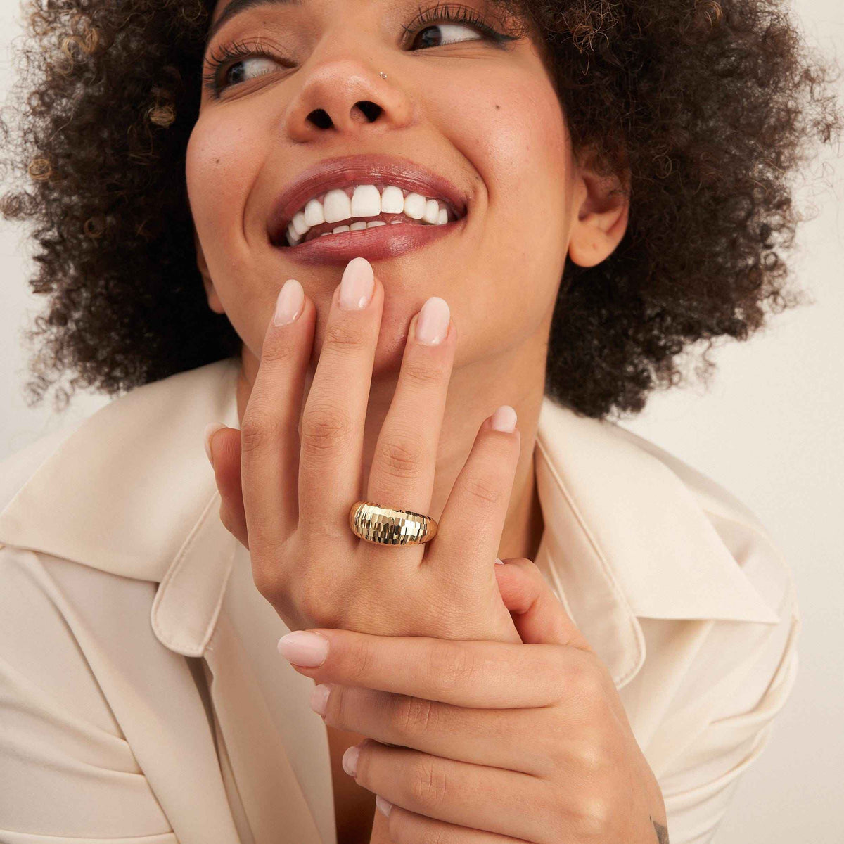 Lächelndes Model mit der Hand am Kinn, trägt einen diamantierten Kuppelring aus 585er Gelbgold