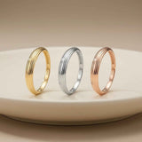 Anillos acanalados en oro amarillo, blanco y rosa de 14 quilates en vertical sobre un plato blanco