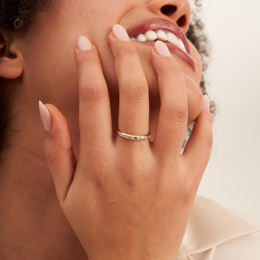 14K yellow gold CZ band ring on hand covering model's smile