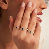 Model wearing 14K yellow gold pear halo rings with lab-grown ruby and emerald