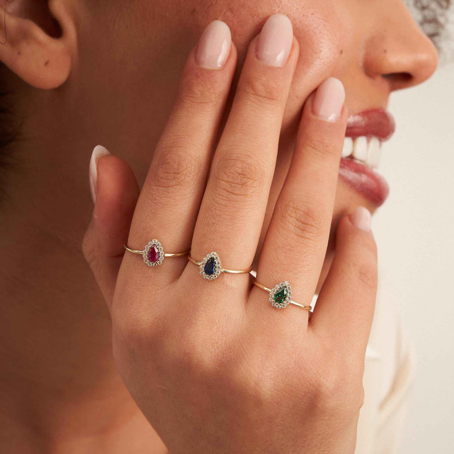 Model wearing 14K yellow gold pear halo rings with lab-grown ruby and emerald