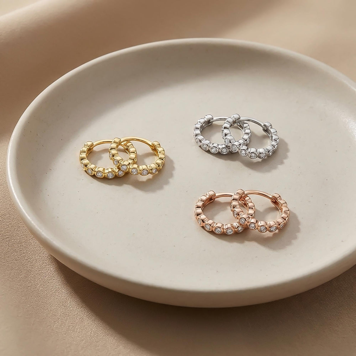 Créoles à oxydes de zirconium en serti clos en or jaune, blanc et rose 14 carats sur une assiette en céramique