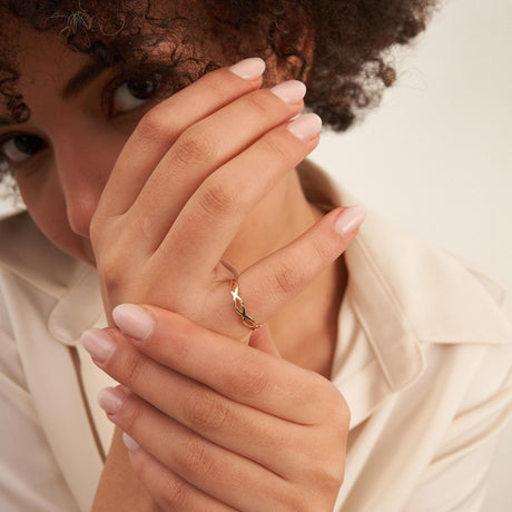 Mannequin, main devant le visage, portant une bague infini ajourée en or jaune 14 carats