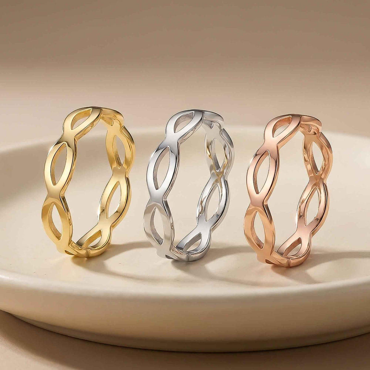 Bagues infini ajourées en or jaune, blanc et rose 14 carats posées debout sur une assiette blanche