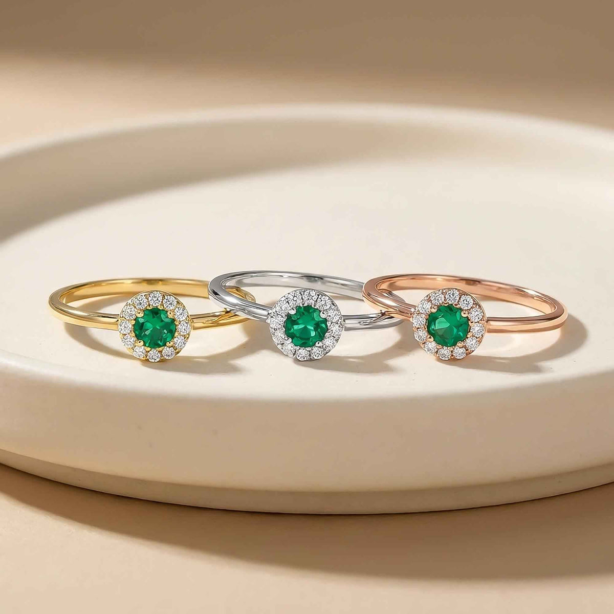 Anelli halo con smeraldo creato in laboratorio in oro giallo, bianco e rosa 14kt su un piedistallo color crema