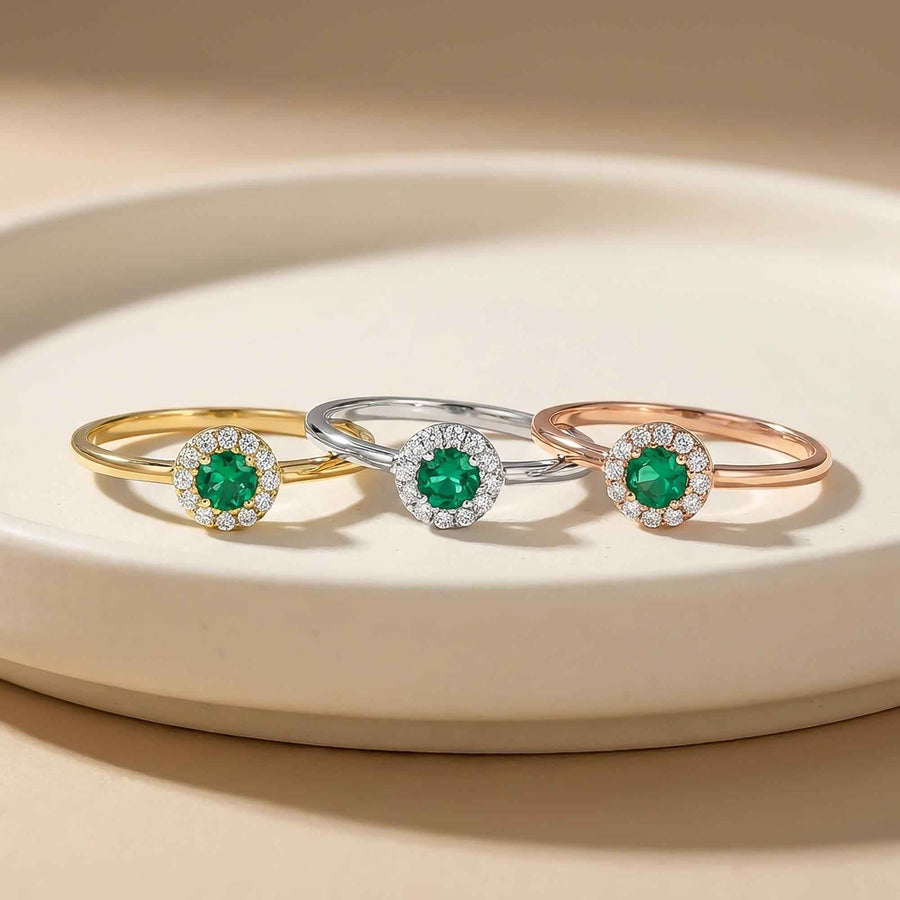 Anelli halo con smeraldo creato in laboratorio in oro giallo, bianco e rosa 14kt su un piedistallo color crema