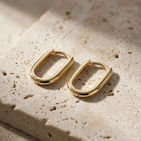 Paire de créoles ovales fines en or jaune 14 carats sur une pierre en travertin