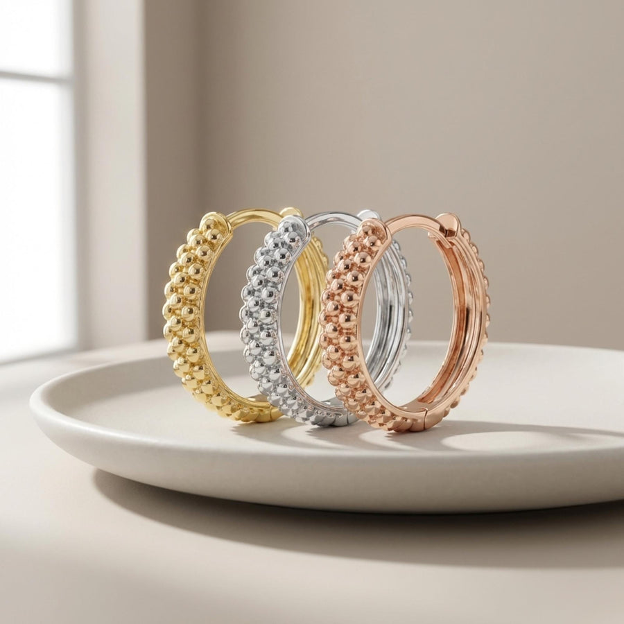 Créoles pointillées en or jaune, blanc et rose 14 carats debout sur une assiette en céramique