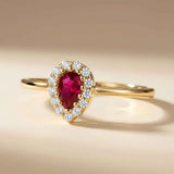 14K yellow gold pear halo ring with lab-grown ruby on beige backdrop