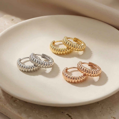 Créoles croissant striées en or blanc, jaune et rose 14 carats sur une assiette en céramique