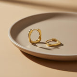 14K yellow gold square hoop earrings on a ceramic dish