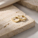 Pair of 14K yellow gold square hoop earrings on travertine stone