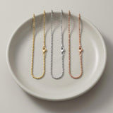 Pulseras de cadena de bolitas en oro amarillo, blanco y rosa de 14 quilates en un plato de cerámica