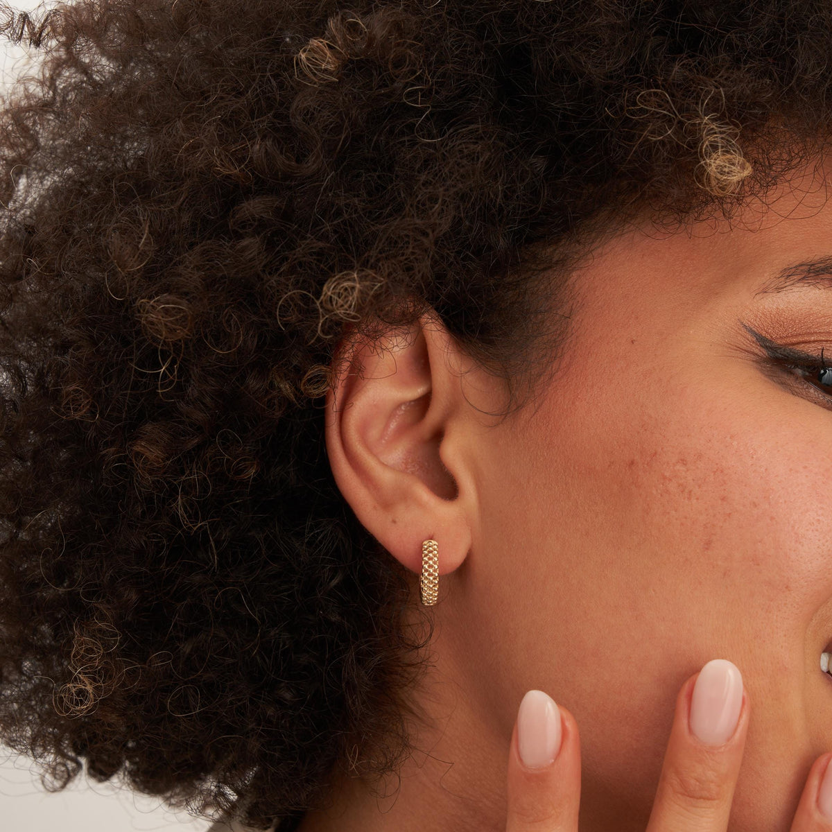 Gros plan de profil sur une créole pointillée en or jaune 14 carats au lobe